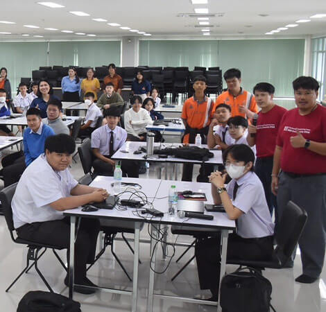 Students sitting and standing in a classroom, giving thumbs up