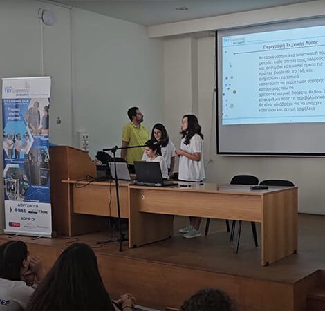 Three female students and their teacher presenting a project display to the class