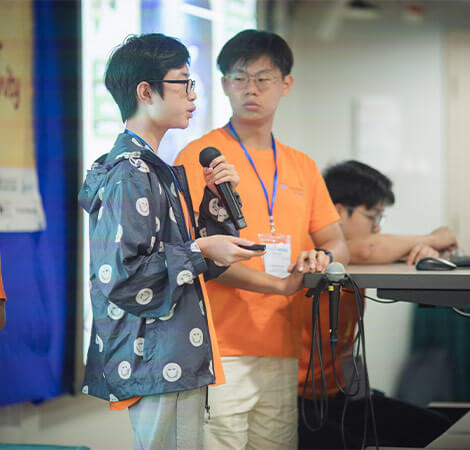 Two students presenting with microphone and handheld clicker.